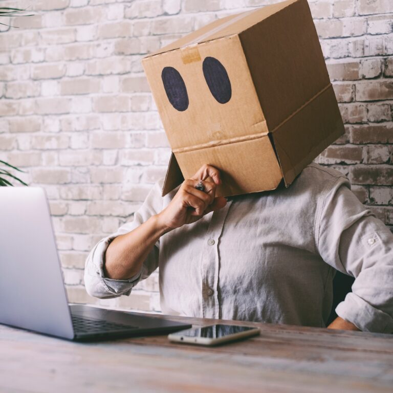 Home worker with carton box on his head. Anonymous people use laptop computer.