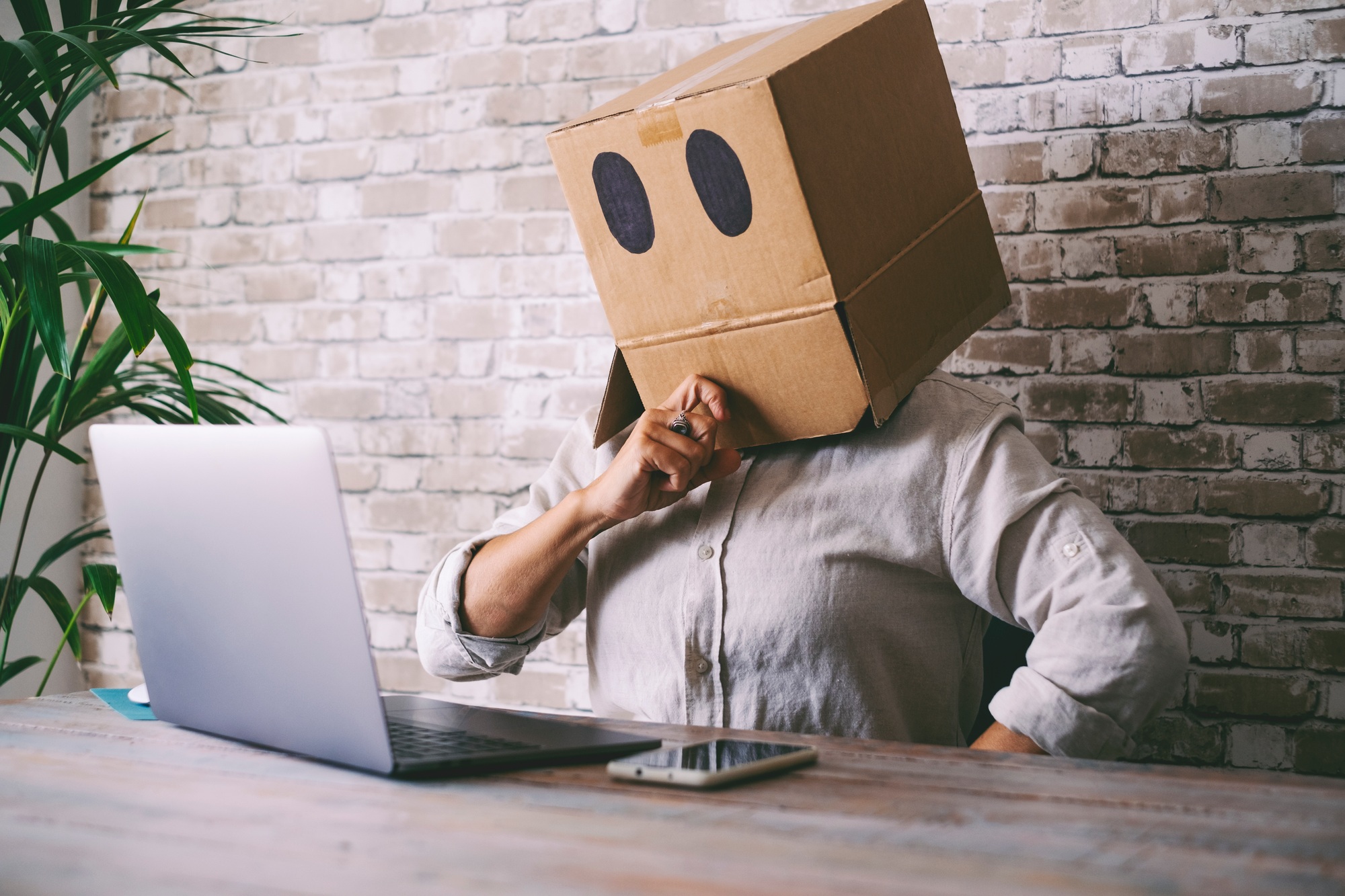 Home worker with carton box on his head. Anonymous people use laptop computer.