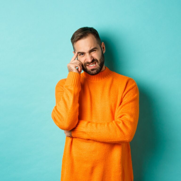 Man with beard, grimacing and cringe from something embarrassing, looking with awkward face